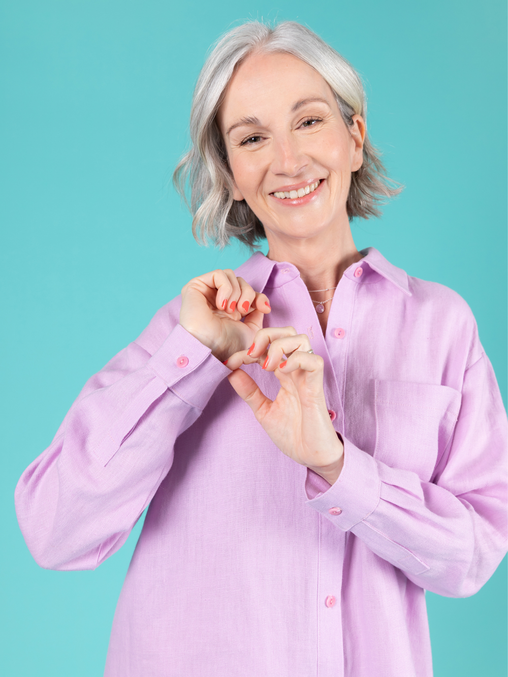 Woman wearing a lilac long sleeve Frida shirt against a teal background.